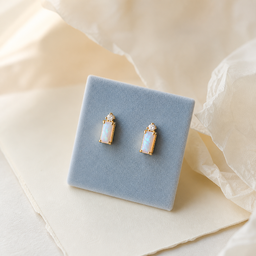 Opal beam stud earrings displayed on a blue jewelry box