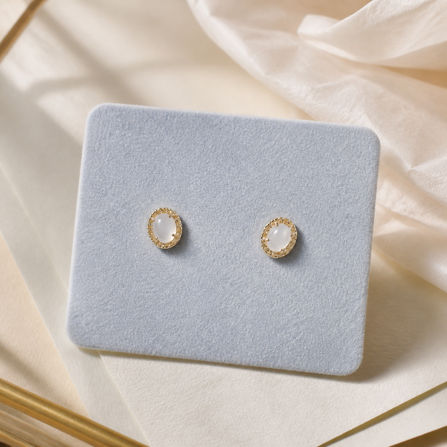 Oval pearl stud earrings on a soft jewelry tray