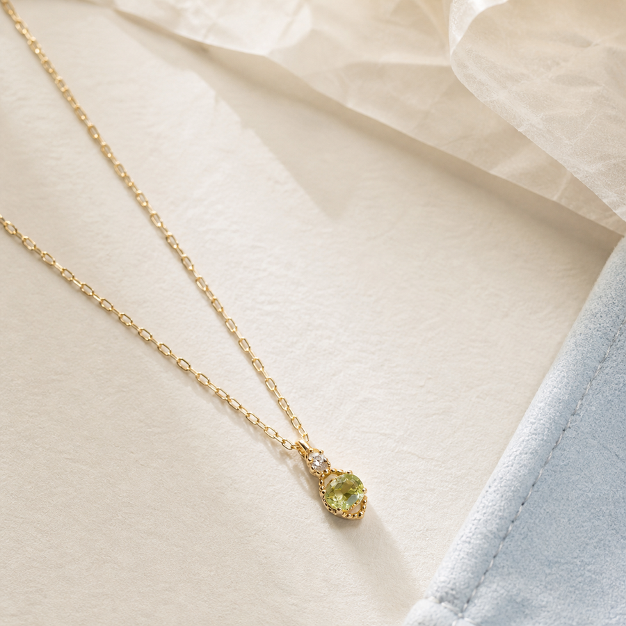 Green dew pendant necklace on textured fabric